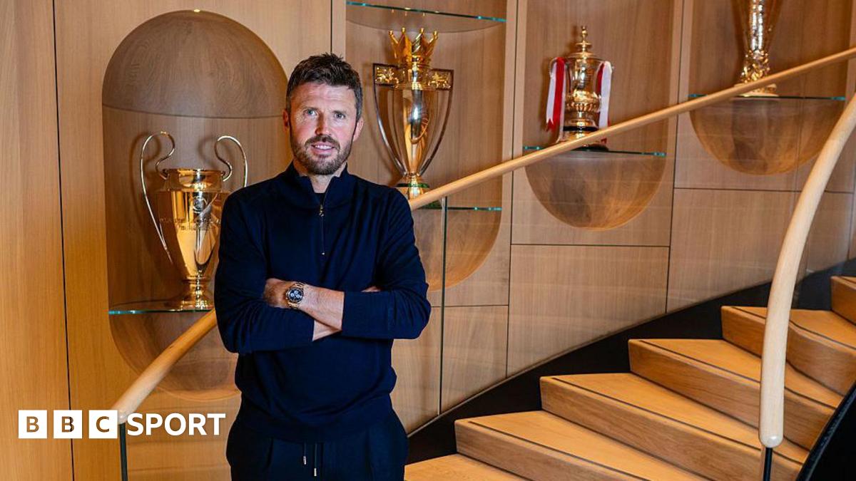 Image of Man United head coach Michael Carrick in front of trophies at Carrington Training Ground