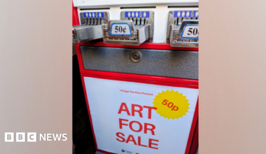 A red, white and silver vending machine with a sign which reads 'Art For Sale'. There is a yellow sticker which says '50p'.