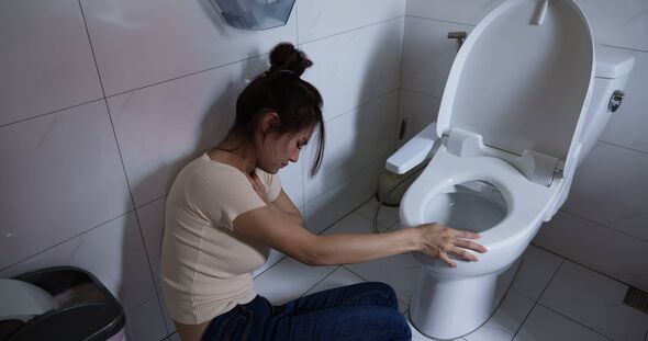 An individual is seated on the floor in a bathroom