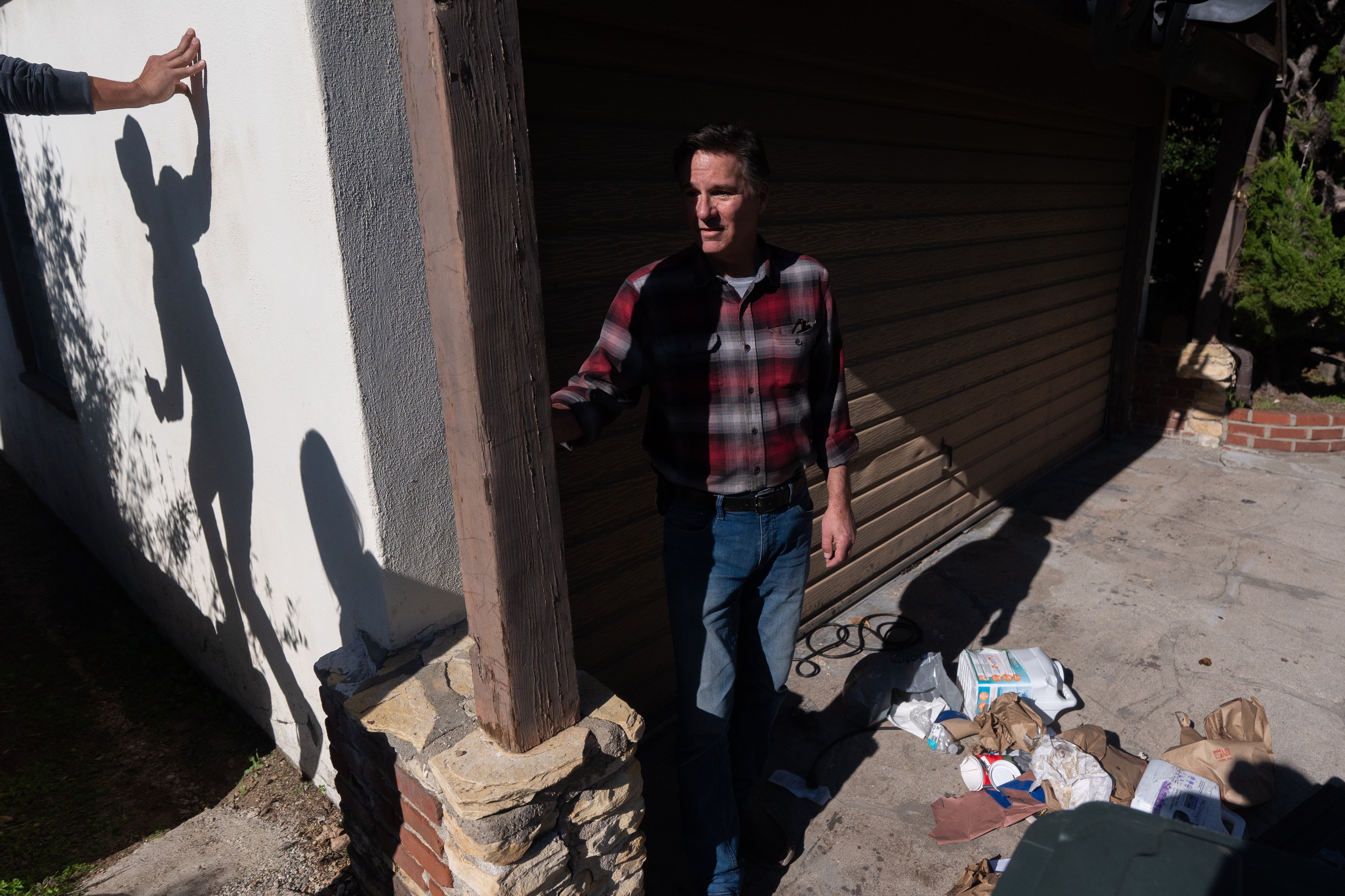 Homeowner Ken Johnson stands outside his house with trash scattered across the driveway after the bear took refuge