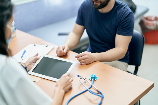 Irreconocible doctor with tablet and irreconocible patient on a table