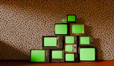 pyramid stack of vintage televisions, each with a vibrant green screen, set against bold leopard-patterned wallpaper and a luxurious red carpet floor.