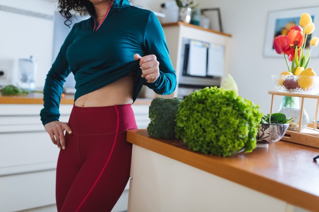 Health-Conscious Woman in Vibrant Kitchen with Green Vegetables and Activewear