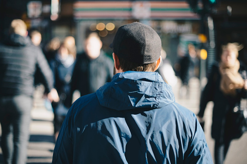 Rear view of man wearing blue jacket on city street during winter