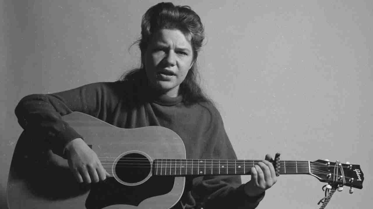 Janis Joplin playing an acoustic guitar in the early 1960s