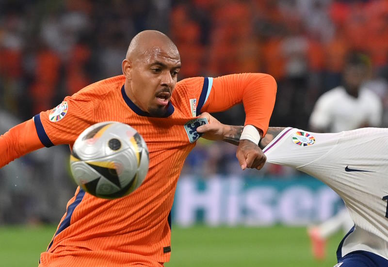 Donyell Malen chests the ball to control it while playing in the orange shirt of the Netherlands