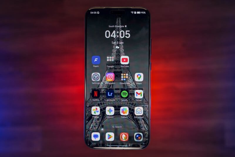 A smartphone with its home screen displayed, showing various app icons including social media, streaming, and productivity apps, against a blurred background with red and blue tones.