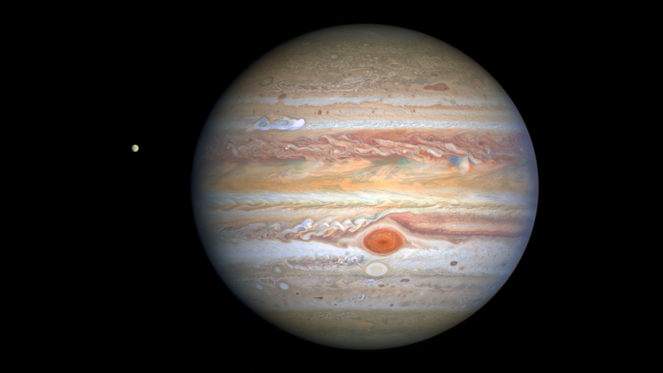 This latest image of Jupiter, taken by NASA&rsquo;s Hubble Space Telescope on August 25, 2020, was captured when the planet was 406 million miles from Earth. Hubble&rsquo;s sharp view is giving researchers an updated weather report on the monster planet&rsquo;s turbulent atmosphere, including a remarkable new storm brewing, and a cousin of the Great Red Spot changing color &ndash; again.A unique and exciting detail of Hubble&rsquo;s snapshot appears at mid-northern latitudes as a bright white stretched-out storm moving at 350 miles per hour (563 kilometers per hour). This single plume erupted on August 18, 2020 and another has since appeared.While it&rsquo;s common for storms to pop up in this region, oftentimes multiple at once, this particular disturbance appears to have more structure behind it than observed in storms of the past. Trailing behind the plume are small, counterclockwise-like dark clumps also not witnessed in the past. Researchers speculate this may be the beginning of a longer-lasting Northern Hemisphere spot, as perhaps a rival to the legendary Great Red Spot that dominates the southern hemisphere.Hubble shows that the Great Red Spot, rolling counterclockwise in the planet&rsquo;s southern hemisphere, is plowing into the clouds ahead of it, forming a cascade of white and beige ribbons. The Great Red Spot is currently an exceptionally rich red color, with its core and outermost band appearing deeper red.Researchers say the Great Red Spot now measures about 9,800 miles across, big enough to swallow Earth. The super-storm is still shrinking as noted in telescopic observations dating back to 1930, but its rate of downsizing appears to have slowed. The reason for its dwindling size is a complete mystery.Another feature researchers are noticing has changed is Oval BA, nicknamed by astronomers as Red Spot, Jr., which appears just below the Great Red Spot in this image. For the past few years, Red Spot, Jr. has been fading in color to its original shade of white after appearing red in 2006. However, now, the core of this storm appears to be darkening to a reddish hue. This could hint that Red Spot, Jr. is on its way to turning to a color more similar to its cousin once again.Hubble&rsquo;s image shows that Jupiter is clearing out its higher altitude white clouds, especially along the planet&rsquo;s equator, where an orangish hydrocarbon smog wraps around Jupiter.The icy moon Europa, potential home for life, is visible to the left of the gas giant.This Hubble image is part of yearly maps of the entire planet taken as part of the Outer Planets Atmospheres Legacy program, or OPAL. The program provides yearly Hubble global views of the outer planets to look for changes in their storms, winds, and clouds.