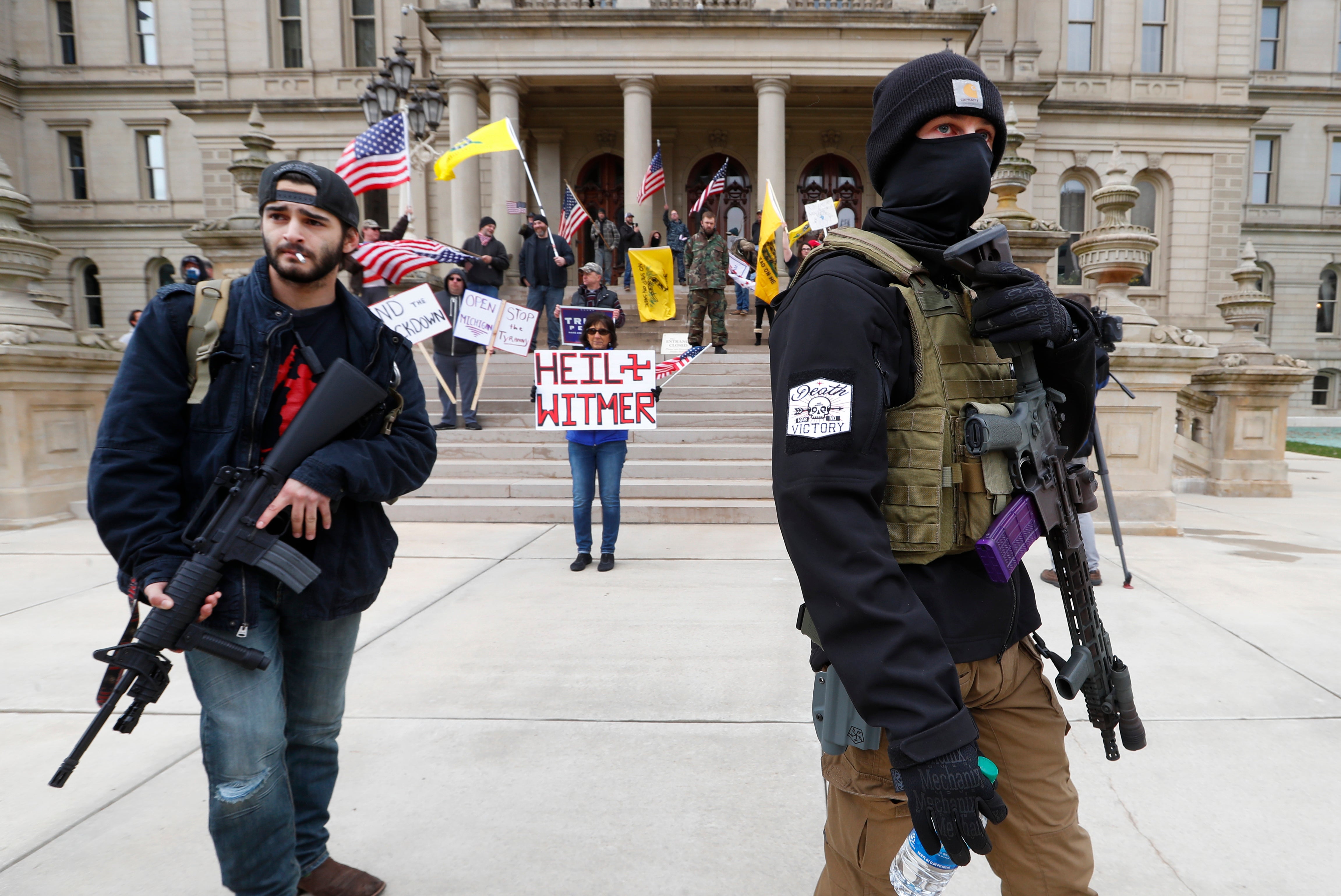 Protesters carry rifles near the steps of the State Capitol building in Lansing, Michigan., on April 15, 2020 during a protest over Governor Gretchen Whitmer's orders to keep people at home and businesses locked during the coronavirus outbreak
