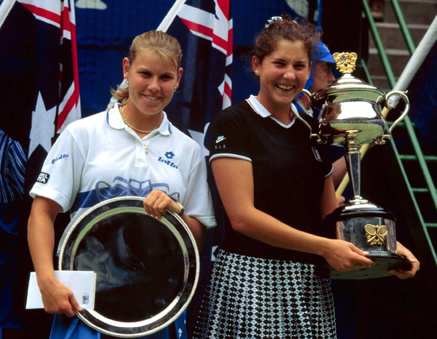 Anke Huber (left) grins next to Monica Seles (right) as they hold the Australian Open runner-up's and winner's trophies respectively.