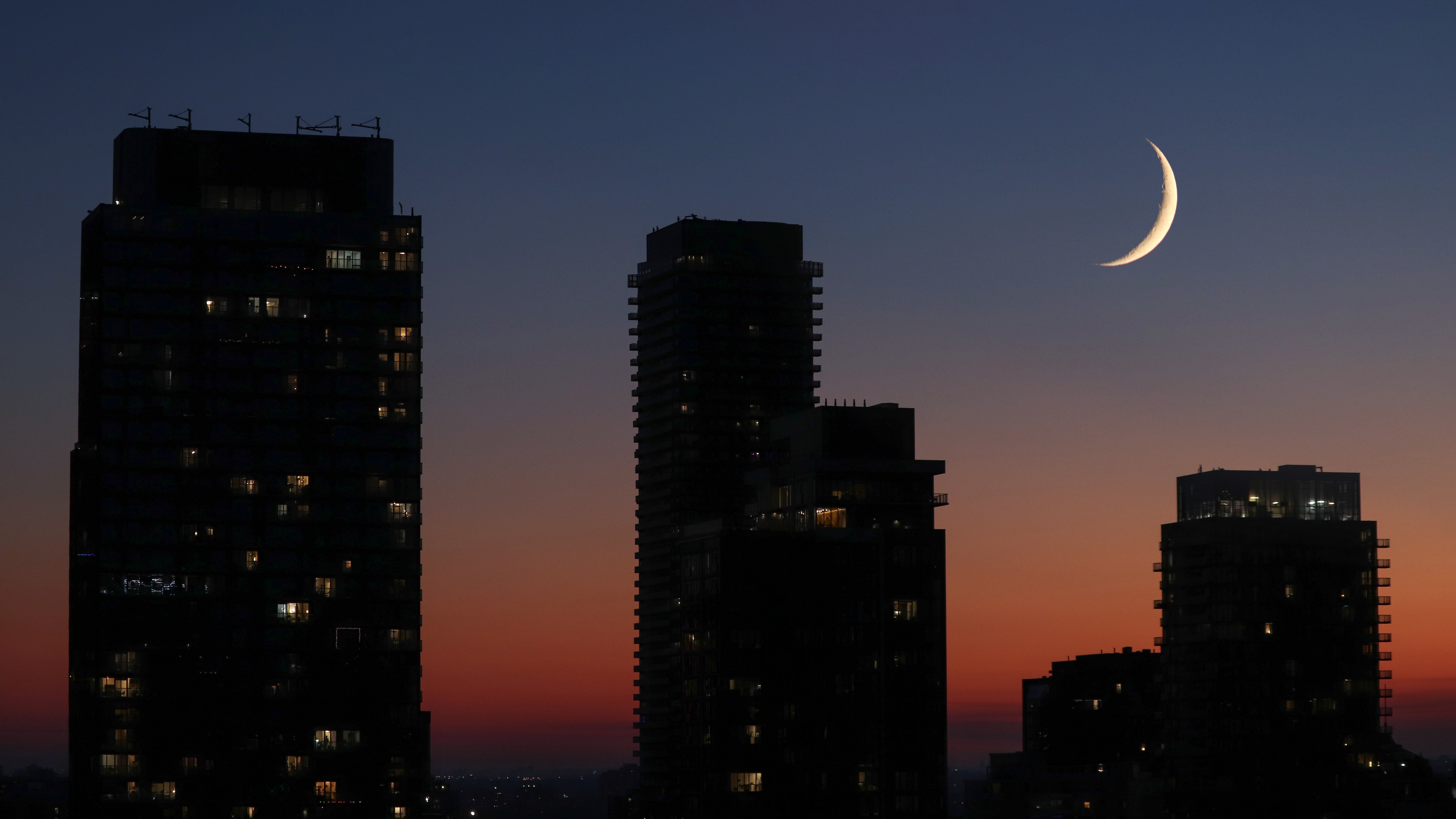 Right after the sunset, the poetic waxing crescent moon of July is setting in company of giants of Toronto .