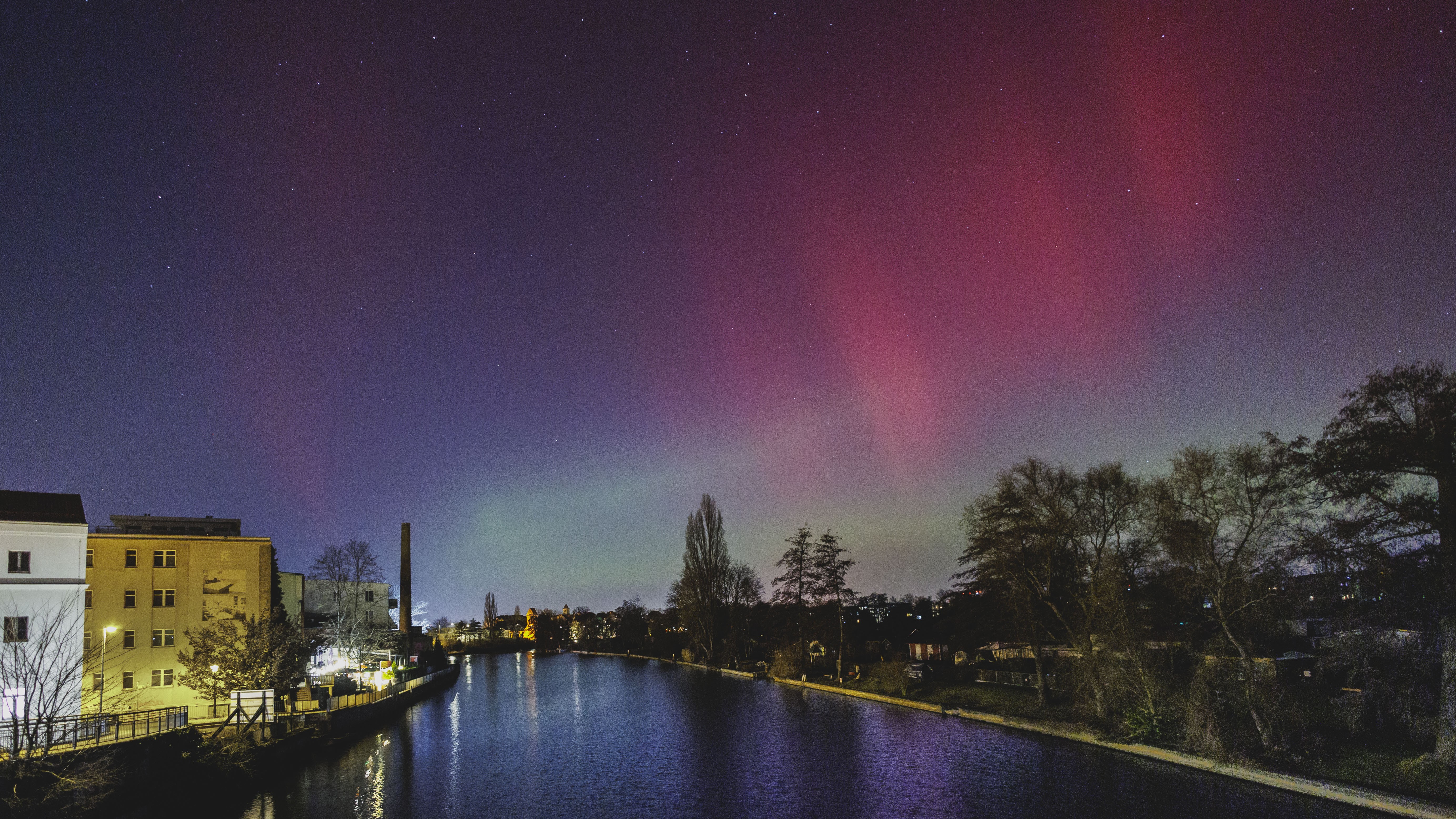 red and green northern lights in the sky above a river
