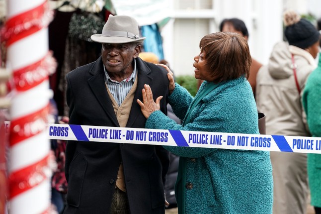 Yolande comforts Patrick as they stand behind police tape on the Square in EastEnders