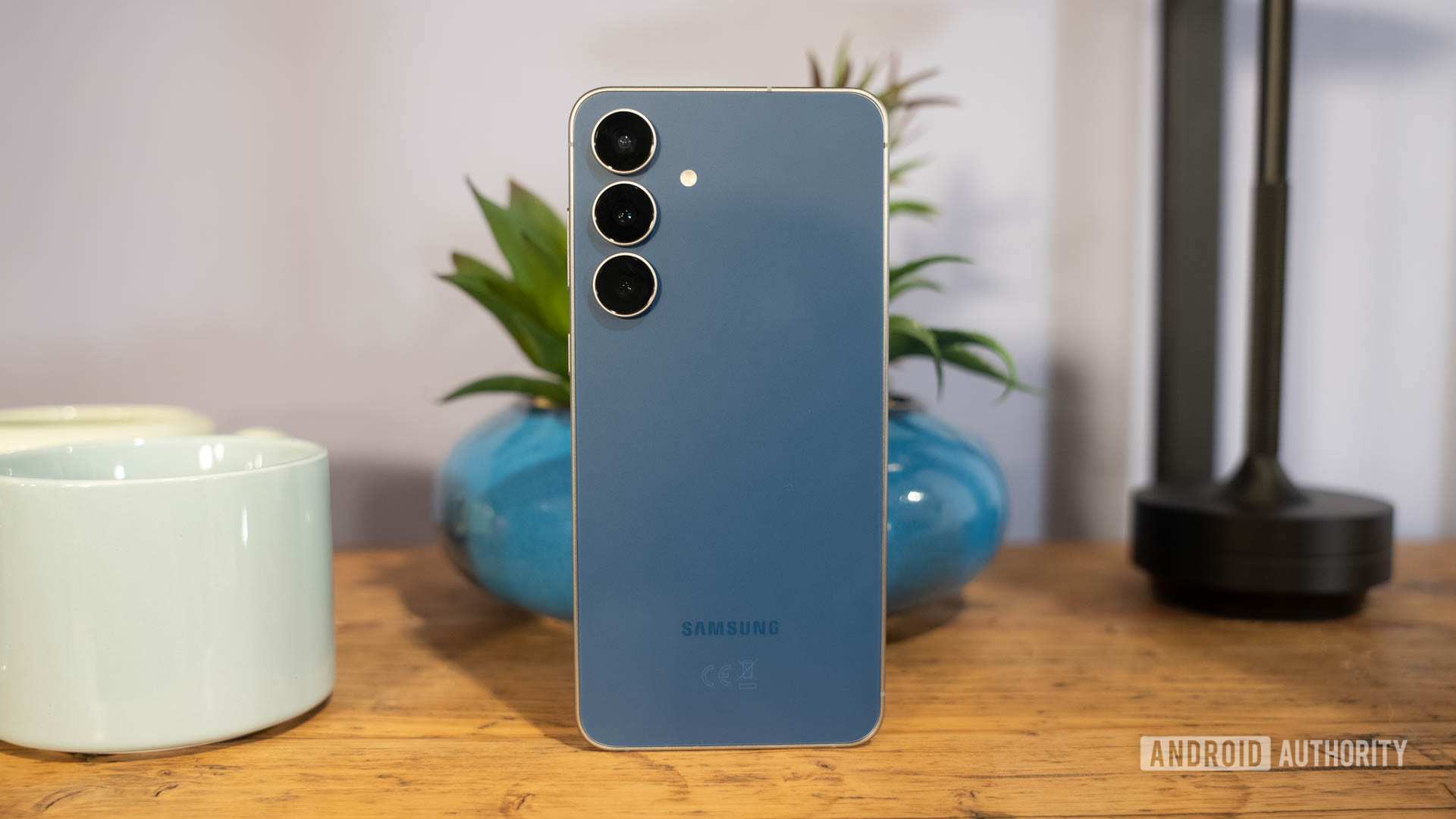 Samsung Galaxy S25 FE in Navy standing in front of plant