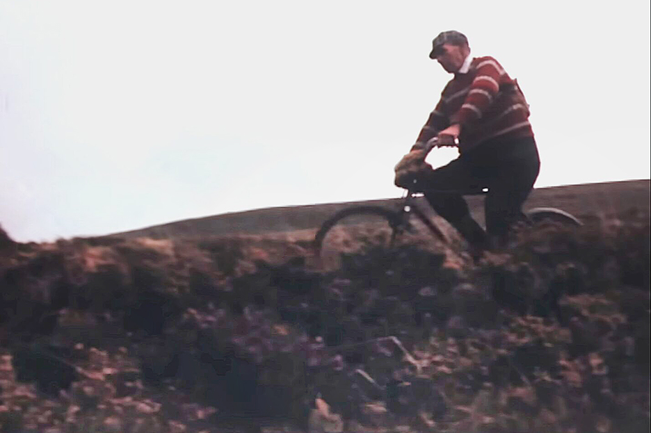 A man crosses a moor on a bike.
