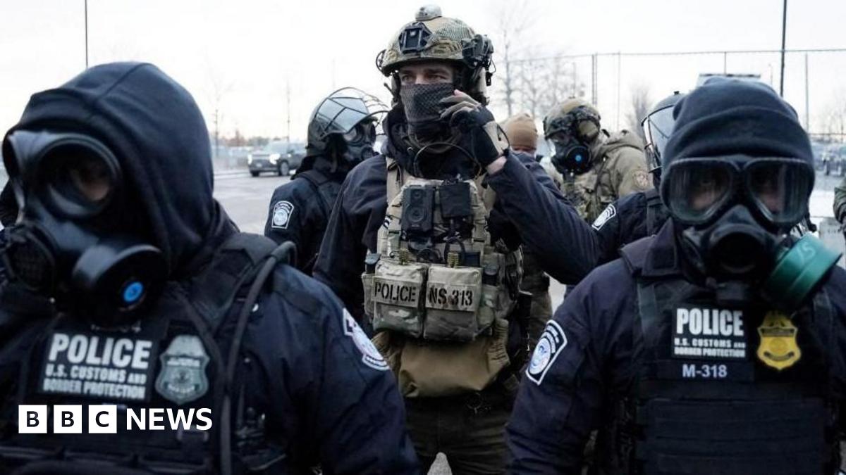 Law enforcement officials wearing heavy military gear and gas masks stand guard during a protest in Minneapolis, Minnesota.