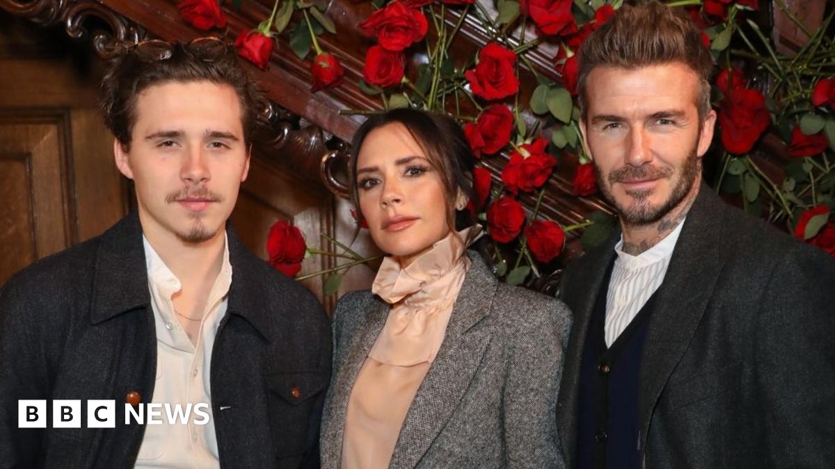 Donald Trump and Keir Starmer sit in a formal drawing room setting  on arm chairs with US and UK  flags behind them. Both have serious expressions and are looking out and not at each other.