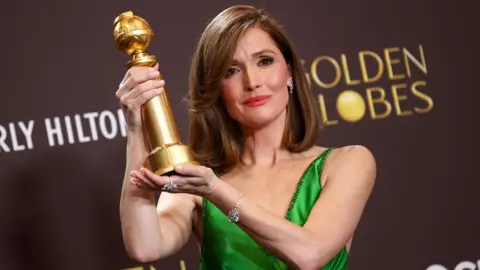 Getty Images Rose Byrne holding up her Golden Globe