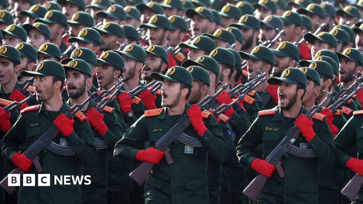 Iranian Revolutionary Guard Corps (IRGC) soldiers march in formation in September 2024. The group of men wear matching green and red uniforms and hold rifles