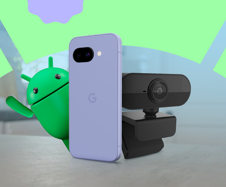 Android mascot peeks from behind a Google Pixel phone placed next to webcam with colorful abstract shapes in the background.