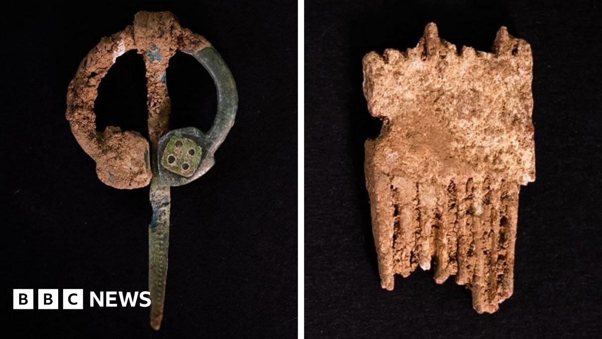 Several fragments of glass arranged in a straight line on a dark surface. They vary in size and shape, and some having a yellow tint and others a green and blue hue. One shard is finely etched with a pattern.