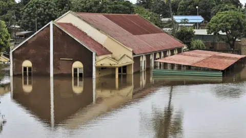 EPA/Shutterstock A large house in Maptuo with flood water seen coming half way up to the windows - with trees behind the building.