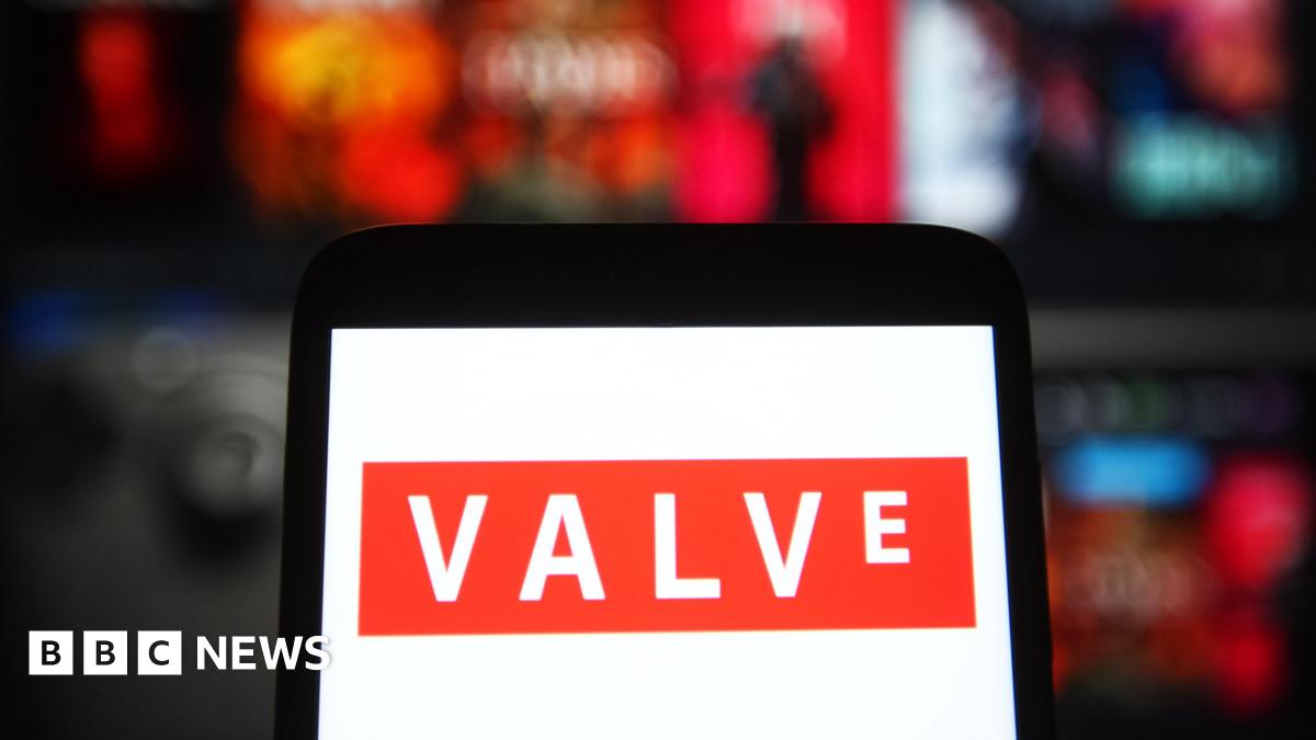 A phone with a white background and the orange logo of Valve Corporation, agianst a blurred background of games on the Steam platform.