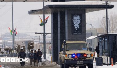 Scene at Iraqi border with Iran, as a vehicle and people pass through a crossing point in the snow