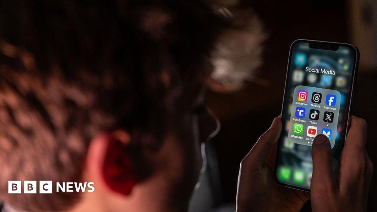 boy on his mobile which is showing social media app icons on the screen