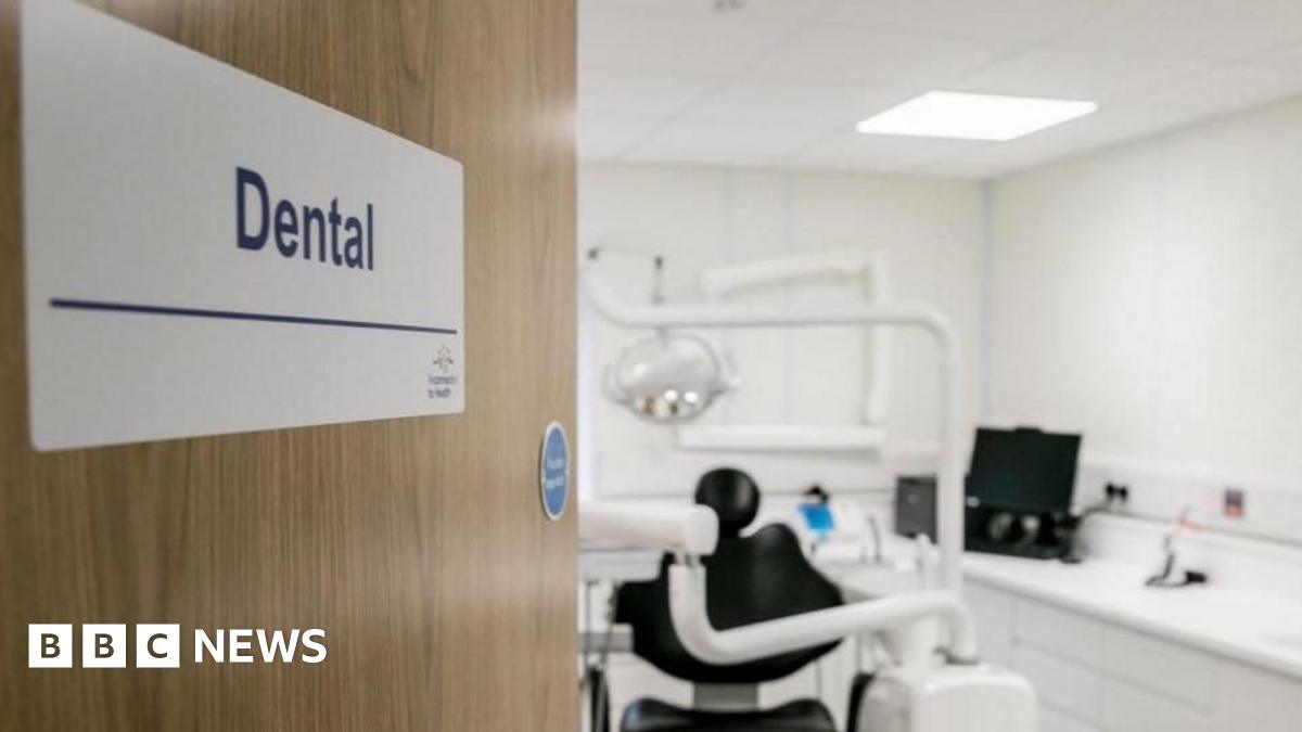 A stock image of a dentist's studio. A door with a signs saying 'dental' opens to a studio with a dentist chair and equipment in the blurred background.
