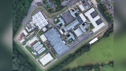 Google A satellite view of a prison surrounded by trees.
