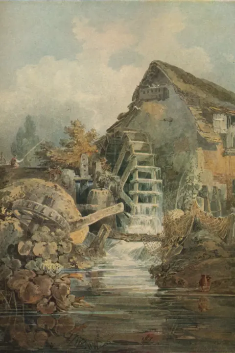 Getty Images Marford Mill, Denbighshire, a water-colour by J. M. W. Turner. An old-fashioned watermill sits beside a calm stream in a rustic countryside setting. The mill has a large wooden waterwheel with cascading water flowing down its paddles, creating a gentle motion. The building is weathered, with a sloping roof covered in moss or thatch, and small windows with white shutters. Fishing nets are draped over rocks near the water’s edge, and clay jugs rest on the ground by the stream. In the foreground, the water reflects the surrounding greenery and stones, while lush plants and flowers grow along the banks. In the background, tall trees rise against a soft, cloudy sky, adding to the tranquil, pastoral atmosphere.