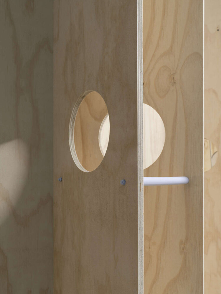 circular cut-outs puncture the plywood partitions
