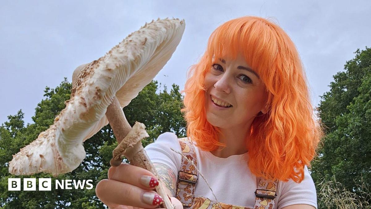 Mrs Gather with bright orange hair holding a large white mushroom
