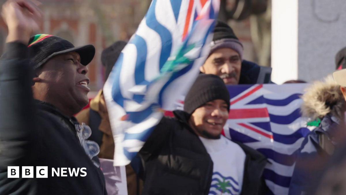 A group of people protest in central London. Some are holding the flag of the British Indian Ocean Territory.