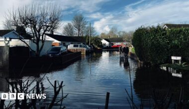 Flooded street at Winterborne Kingston in Dorset. People are seen walking through the water.