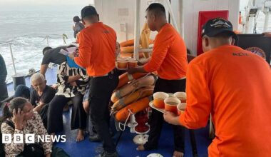 Distressed passengers sitting on the floor after being rescued by Philippine Coast Guard who are handing out bread and soup