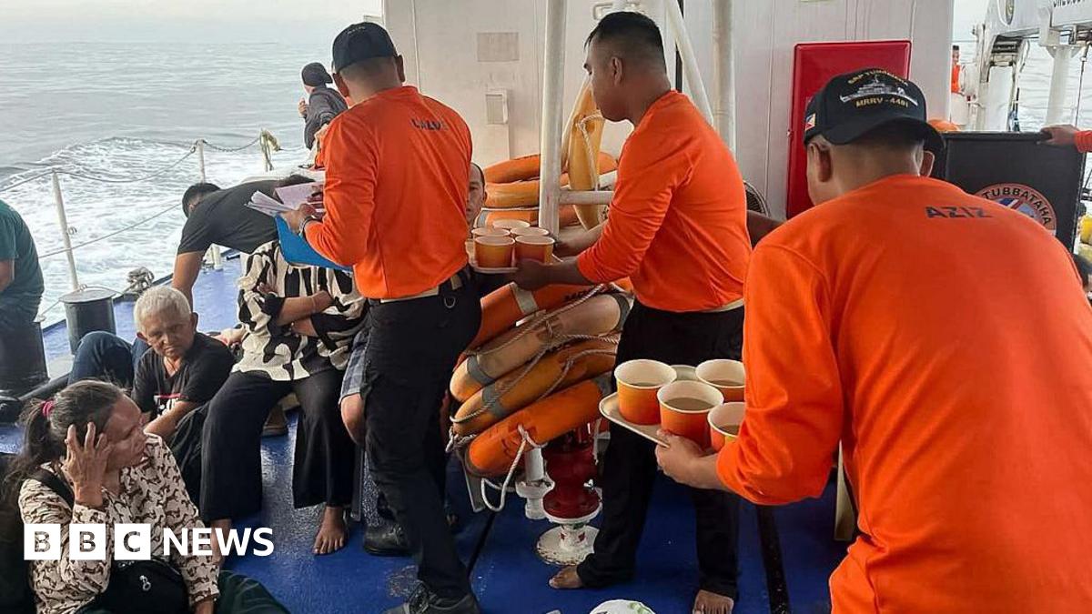 Distressed passengers sitting on the floor after being rescued by Philippine Coast Guard who are handing out bread and soup