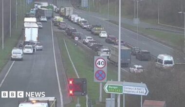 A woman wearing a dark hijab and black dress walks past a mural on a wall depicting politicians from the US and Iran sitting opposite each other, taken in Tehran on 28 January.