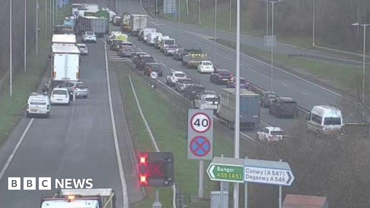 A woman wearing a dark hijab and black dress walks past a mural on a wall depicting politicians from the US and Iran sitting opposite each other, taken in Tehran on 28 January.