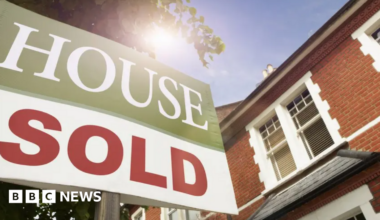 Stock image of a 'house sold' sign in front of a property.