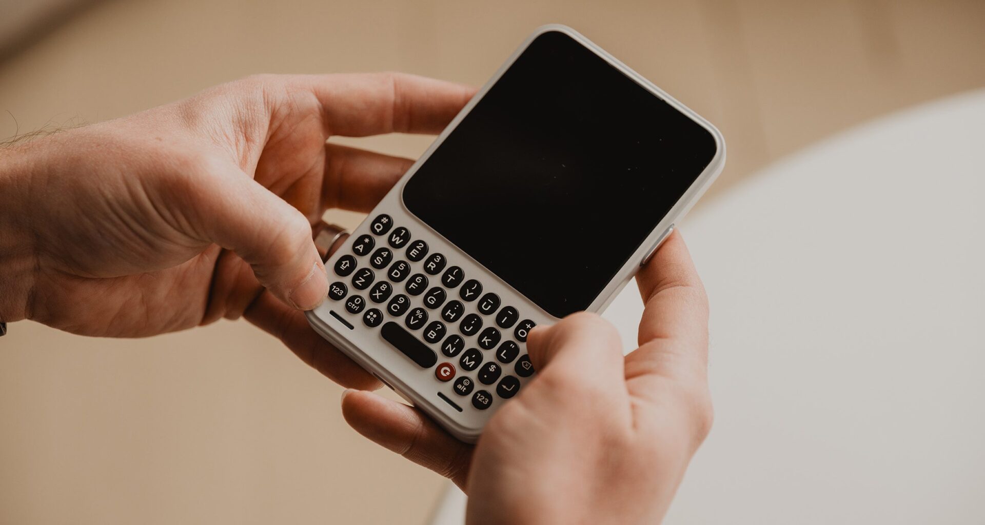 Photo of a person's hands holding the Clicks Communicator phone as if to type on the QWERTY keyboard