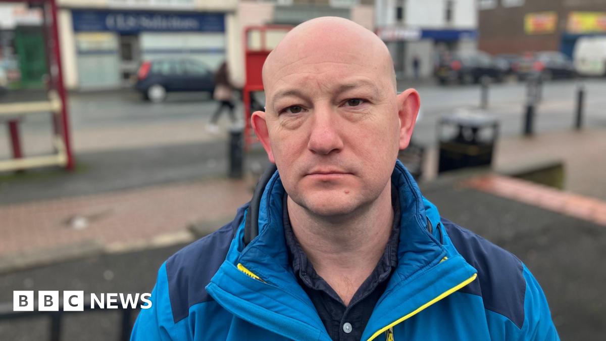 A man in a bright blue jacket stands in Featherstone