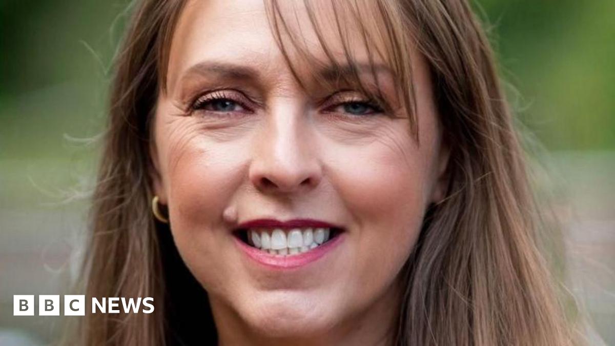 Donald Trump and Keir Starmer sit in a formal drawing room setting  on arm chairs with US and UK  flags behind them. Both have serious expressions and are looking out and not at each other.