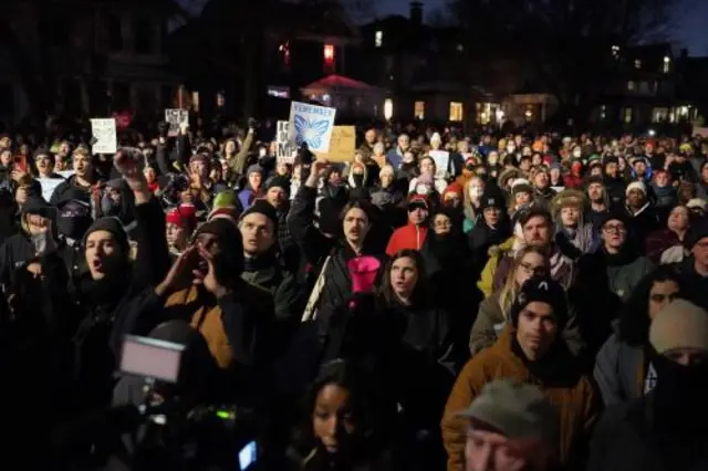 A large crowd holds up signs at a vigil
