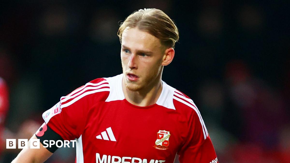 Finley Munroe, slightly leaning towards his left, has the ball at his feet for Swindon