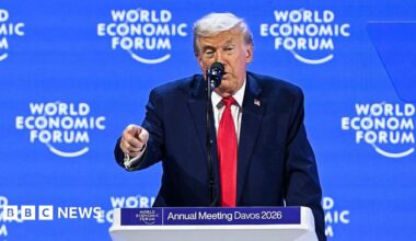 Donald Trump delivers a speech from a lectern at the World Economic Forum in Davos wearing a navy suit, red tie and a US flag pinned to his suit.