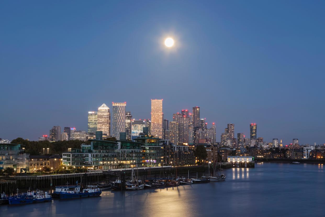 England, London, Full Moon over Docklands and Canary Wharf Skyline at Night
