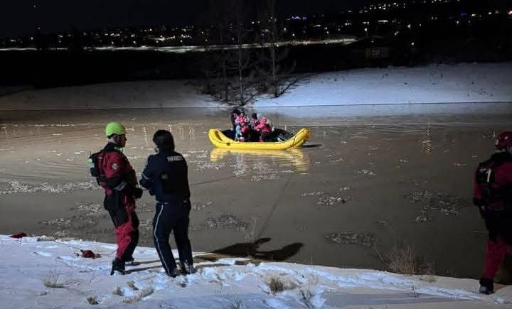 Several people on a yellow raft on a road submerged in water