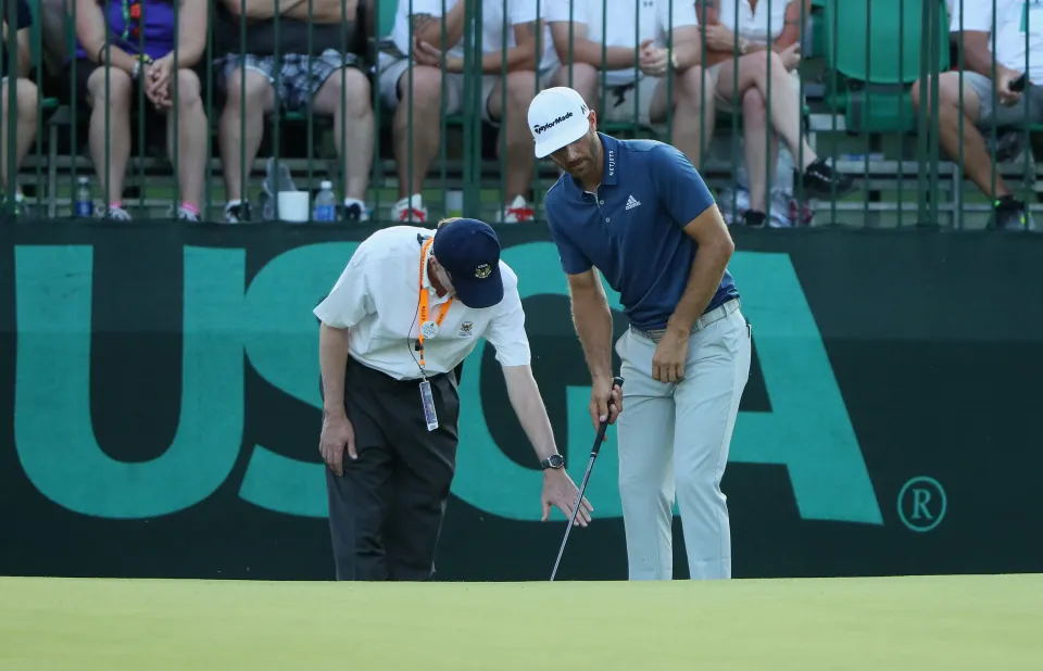 Dustin Johnson of the United States chats with a rules official behind the 16th green during the final round of the U.S. Open at Oakmont Country Club on June 19, 2016 in Oakmont, Pennsylvania.